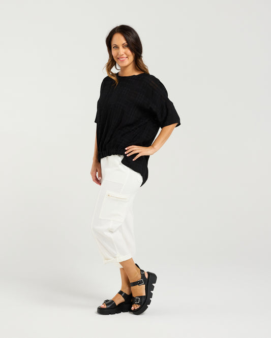 Lady in Black Nikita Top with White 3/4 pants and a white background