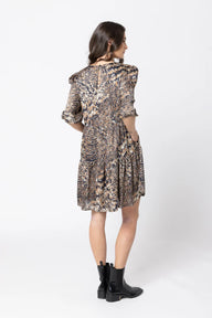Woman wearing a patterned dress and black boots on a white background