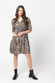 Woman wearing a patterned dress and black boots on a white background