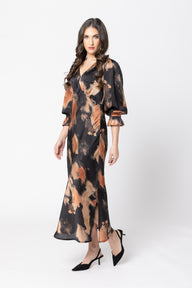 Woman wearing a long, patterned dress on a white background