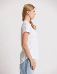 Woman wearing a white t-shirt and light blue jeans against a plain background