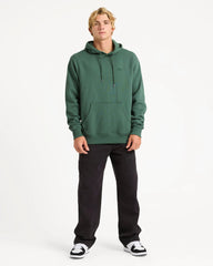 Person wearing a green hoodie and black pants on a white background