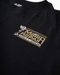 Close-up of a black crewneck t-shirt featuring a distressed gold and white graphic on the left chest that reads 'Motor Repair Salty Crew' with a wrench illustration.