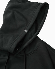 Close-up of a black pullover hoodie with a small white Vans logo tag on the inside of the hood, set against a plain white background.