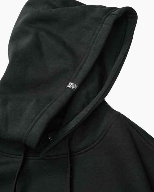 Close-up of a black pullover hoodie with a small white Vans logo tag on the inside of the hood, set against a plain white background.