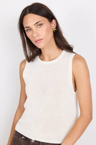Woman wearing a white sleeveless top against a plain background