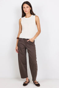 Woman wearing a white sleeveless top and brown pants on a white background