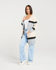 Woman wearing a striped cardigan, white shirt, and light blue jeans on a white background