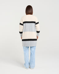 Person wearing a striped sweater and light blue jeans on a plain background
