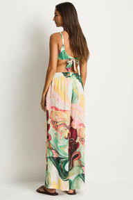 A woman shown from the back wearing a two-piece swimsuit with a green and white patterned halter top and matching high-waisted, wide-leg maxi pants featuring a colorful abstract swirl print.