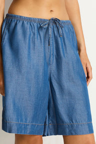 Blue denim shorts worn by a person on a white background