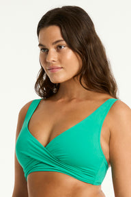 Woman wearing a green bikini top against a white background