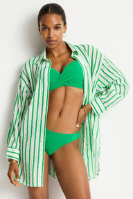 Woman wearing a green bikini with a matching striped shirt on a white background