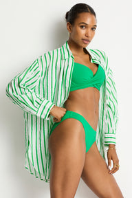 Woman wearing a green bikini with a matching shirt against a white background