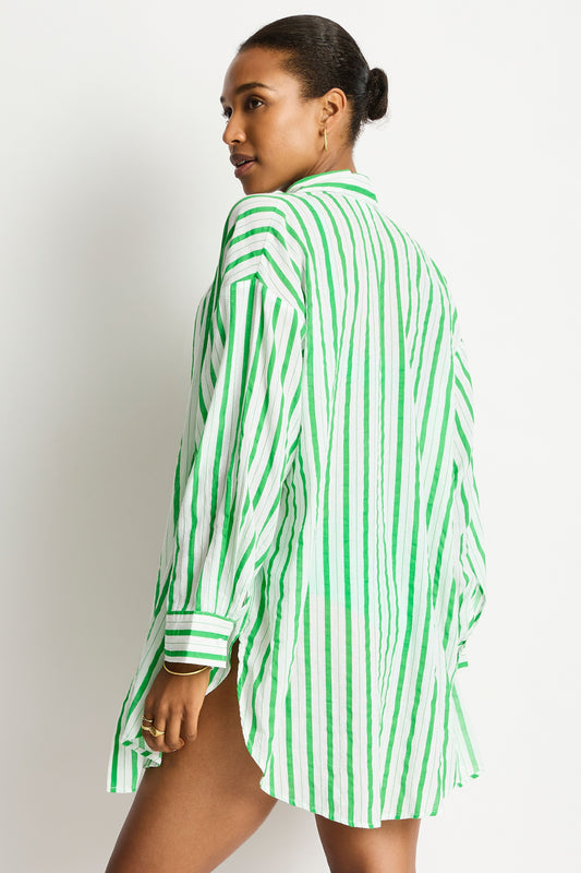 Woman wearing a green and white striped shirt against a plain background