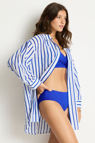Woman wearing a blue and white striped cover-up over a blue bikini.