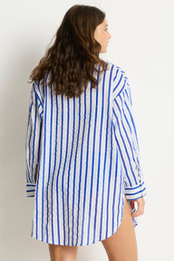 Woman wearing a blue and white striped shirt against a plain background