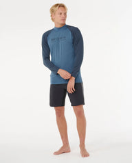 Man wearing a blue long-sleeve rash guard and black shorts on a white background