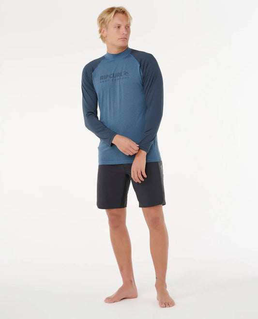 Man wearing a blue long-sleeve rash guard and black shorts on a white background