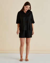 Woman wearing a black outfit against a beige background