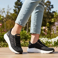Person wearing black sneakers with white soles on a wooden surface with a blurred natural background
