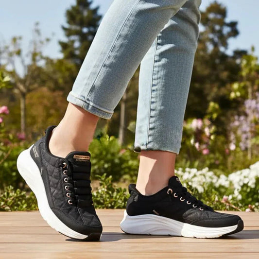 Person wearing black sneakers with white soles on a wooden surface with a blurred natural background