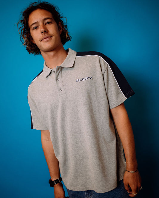 Person wearing a gray and Navy polo shirt with a logo against a blue background