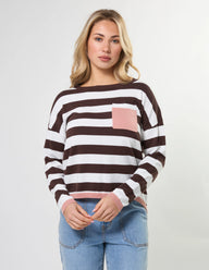 Woman wearing a brown and white striped sweater with a pink pocket on a light gray background