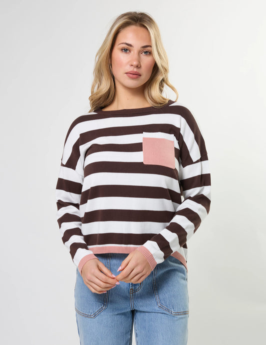 Woman wearing a brown and white striped sweater with a pink pocket on a light gray background
