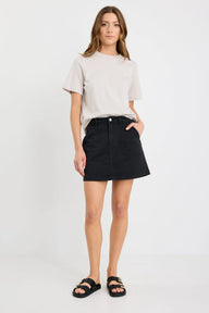 Woman wearing a beige t-shirt and black skirt on a white background