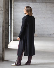 Woman wearing a black long coat in an industrial setting