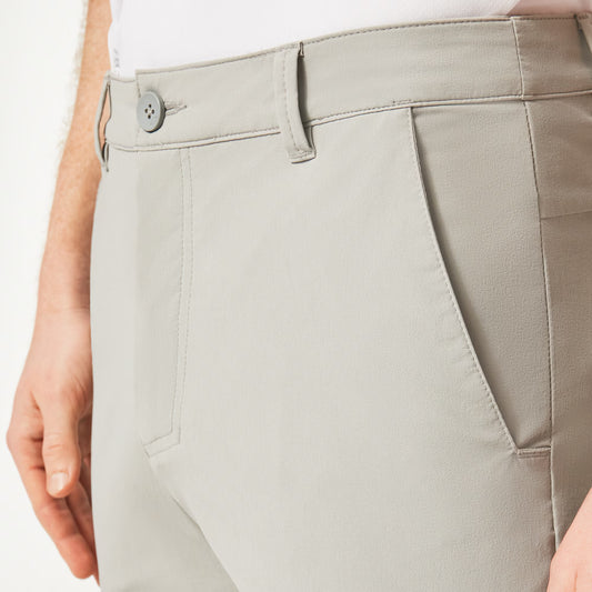 Close-up of light gray pants with a button on a white background