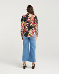 Person wearing a floral blouse and blue jeans on a white background