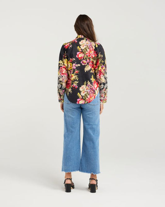 Person wearing a floral blouse and blue jeans on a white background