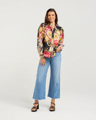 Woman wearing a colorful floral blouse and blue jeans on a white background