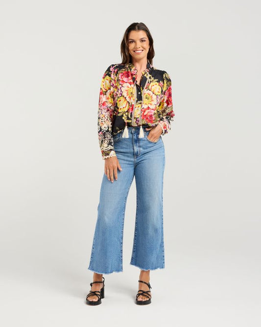 Woman wearing a floral blouse and blue jeans on a white background