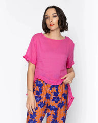 Woman wearing a bright pink top and colorful pants on a white background