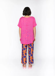 Person wearing a pink top and floral pants on a white background