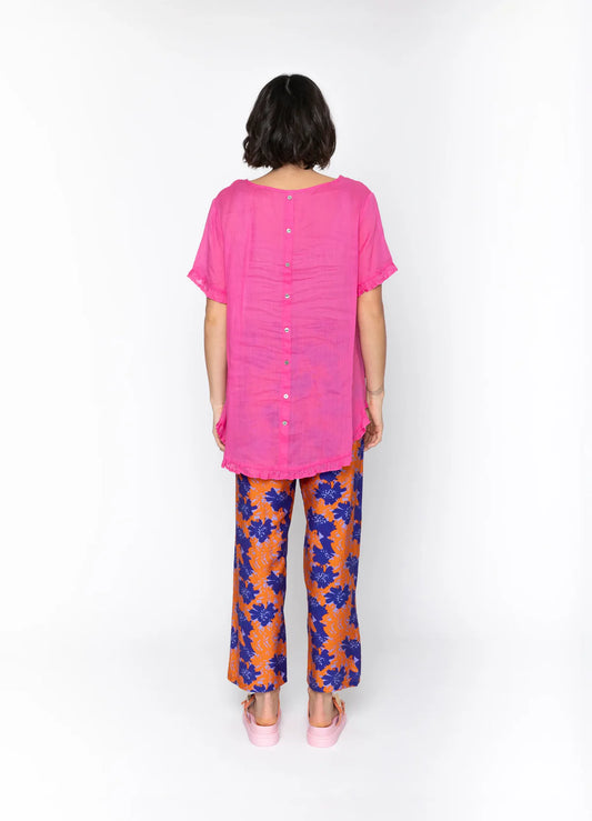 Person wearing a pink top and floral pants on a white background