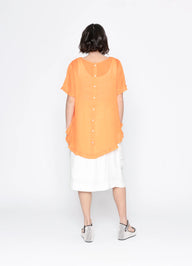 Person wearing an orange top and white skirt on a white background