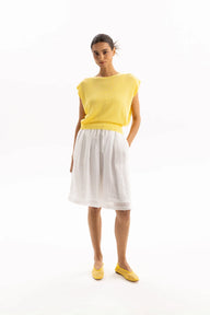 Woman wearing a yellow top and white skirt on a white background