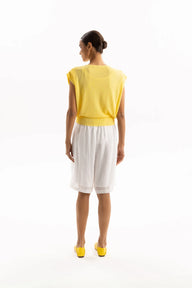 Woman wearing a yellow top and white skirt on a white background