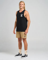 Man wearing a black tank top with a logo, tan shorts on a gray background
