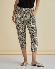 Person wearing leopard print capri pants against a beige background