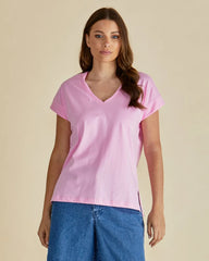 Woman wearing a pink t-shirt and blue jeans against a beige background