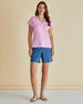 Woman wearing a pink top and blue shorts on a plain background
