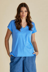 Woman wearing a blue t-shirt and jeans against a beige background