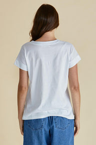 Person wearing a plain white t-shirt and blue jeans on a beige background