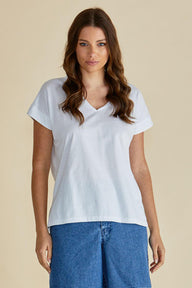 Woman wearing a light blue t-shirt and blue jeans against a beige background
