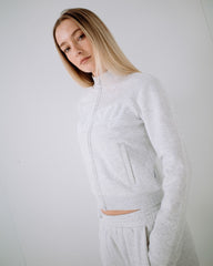 Woman wearing a light gray tracksuit against a white background